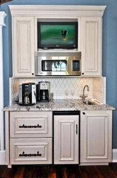 a kitchen with white cabinets and granite counter tops, microwave above the stove and coffee maker