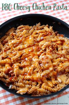 a skillet filled with cheesy pasta on top of a checkered table cloth