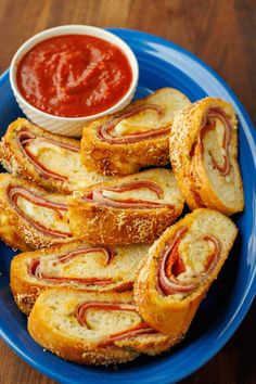 a blue plate topped with pastries next to a bowl of ketchup and dipping sauce