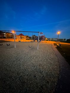 an empty playground at night with swings and lights