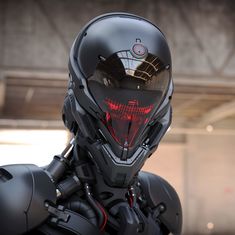 a futuristic man wearing a black helmet with red light on his face and hands in front of him