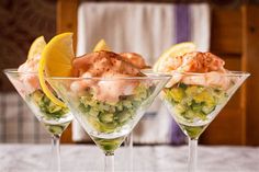 three martini glasses filled with different types of food