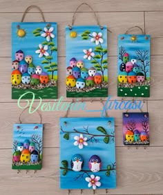 four colorful paintings hanging on the wall in front of a wooden floor with flowers and owls