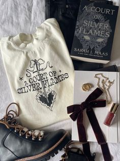 an assortment of clothing, shoes and jewelry laid out on top of a white sheet