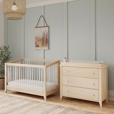 a baby crib next to a dresser in a room with blue walls and wooden floors