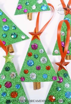 three christmas trees made out of green glitter and red ribbon with bows on them, sitting next to each other