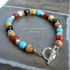 "This is a southwestern inspired men's bracelet that I handcrafted by combining natural semi-precious gemstone beads: Tiger Eye with beautiful golden brown luster, teal blue Magnesite (as known as Magnesite Turquoise), Red Jasper in rich brick red, and earthy looking Picture Jasper. I accentuated with silver-tone pewter beads and spacers to add a touch of tribal flavor, and finished off with a tribal style toggle clasp. A lobster claw clasp option is also available. All metal materials are lead- Southwestern Natural Stones Beaded Bracelet Gift, Southwestern Gemstone Beads Bracelet For Healing, Southwestern Gemstone Beads Healing Bracelet, Southwestern Style Healing Gemstone Beads Bracelet, Southwestern Style Beaded Bracelets With Gemstone Beads, Southwestern Beaded Bracelets For Jewelry Making, Southwestern Gemstone Beaded Bracelets For Healing, Southwestern Style Adjustable Gemstone Beads Bracelets, Southwestern Style Beaded Bracelets With Round Beads For Healing