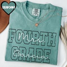 a t - shirt with the words fourth grade on it next to some shoes and a hat