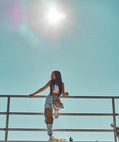 a woman riding a skateboard up the side of a metal rail under a blue sky