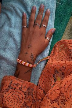 a woman's hand with tattoos on her left arm, and an orange lace dress