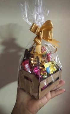 someone is holding up a small gift box filled with chocolates and candy bar wrappers