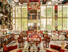 a room filled with lots of books and furniture next to large windows in front of them