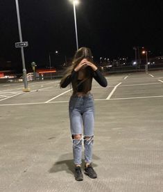 a woman standing in an empty parking lot at night