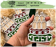 a hand holding two christmas themed stickers in front of some fake trees and snowflakes