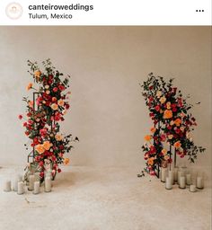 two tall vases with flowers and candles are arranged in the shape of an arch