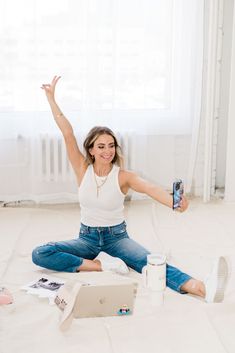 a woman is sitting on the floor with her arms in the air