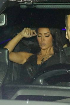 a man and woman sitting in the driver's seat of a car at night