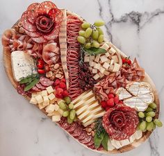 an assortment of cheeses, meats and vegetables on a platter