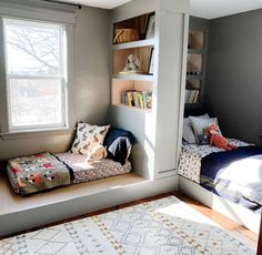 a room with two beds and a rug on the floor in front of it, next to a window