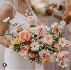 two bridesmaids holding bouquets of flowers in front of each other on their wedding day