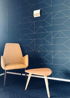 a chair and ottoman in front of a blue wall with geometric designs on it, next to a toilet paper dispenser