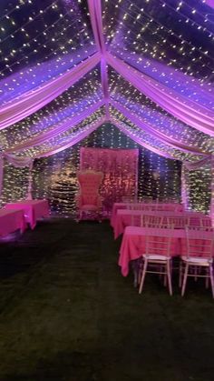 the inside of a tent decorated with pink and white lights