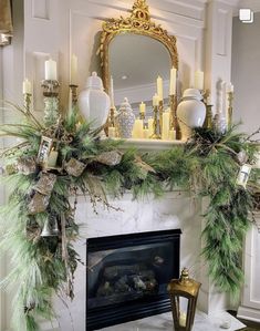 a mantel decorated with greenery and candles in front of a mirror on top of a fireplace