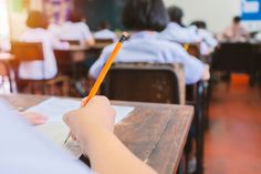 a person sitting at a desk with a pencil in their hand