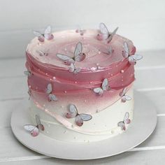 there is a pink and white cake with butterflies on it