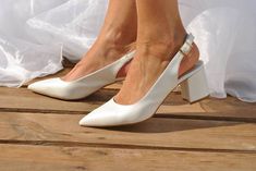 a woman wearing white high heels standing on a wooden platform