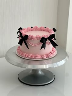 a pink and black cake sitting on top of a silver platter next to a white wall