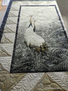 a quilted table runner with two cranes on it