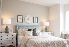 a bedroom with white furniture and gray walls, including a bed that has pillows on it