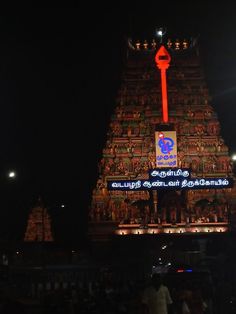 an illuminated temple in the night with people standing around it