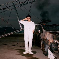 a man in white standing next to a car