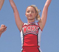 a girl in a cheerleader uniform holding up her arms