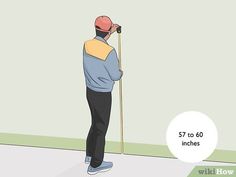 a man standing in front of a wall holding a stick and looking at the ground