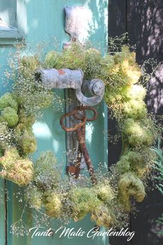 a wreath is hanging on the side of a door with an old rusty wrench