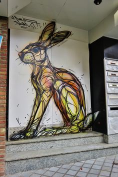 a large rabbit painted on the side of a building next to some stairs and graffiti