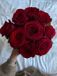 a woman's hand holding a bouquet of red roses