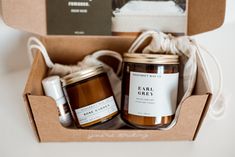 an open box containing two jars of candles