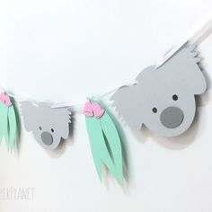 paper koalas are hanging on a string with pink bows and mint green leaves