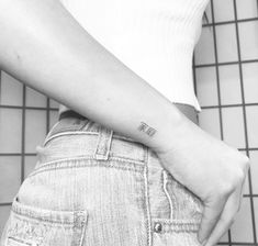 a woman with a small tattoo on her left arm is standing in front of a tiled floor