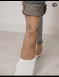 a woman's foot with tattoos on it and her leg in grey jeans, white socks