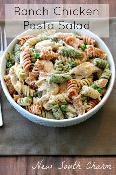 a white bowl filled with pasta salad on top of a wooden table next to a fork