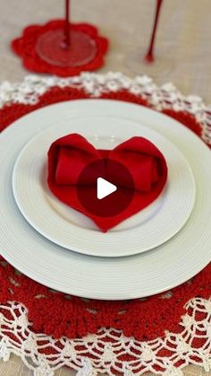 a white plate topped with red napkins on top of a doily covered table