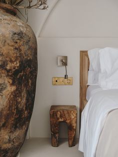 a large vase sitting next to a bed on top of a white floored room