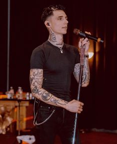 a man with tattoos on his arms holding a microphone