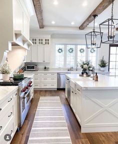 a large kitchen with white cabinets and wood flooring, along with an area rug