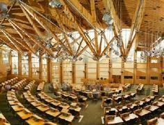 the interior of a large wooden building with rows of tables and chairs on each side